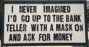 quarantine joke on an old school marquee with changeable letters that says, I never imagined I'd go up to the bank teller with a mask on and ask for money